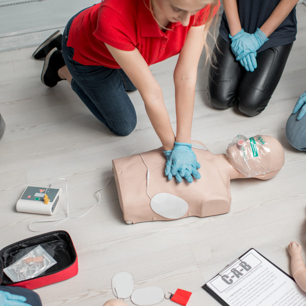 Kvinna visar defibrillering på en HLR docka. 