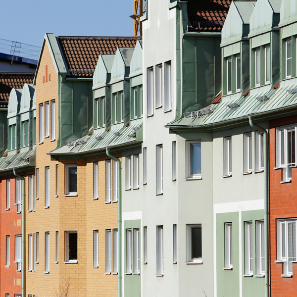 Lägenhetshus från en vy utomhus en solig dag i färgerna orange, grön och terracotta.