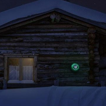 Timmerstuga i snön med ett lysande grönt skåp för hjärtstartare utomhus. 