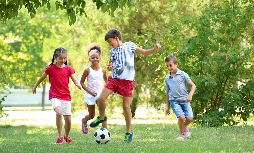 Fyra barn leker glatt tillsammans med en fotboll.