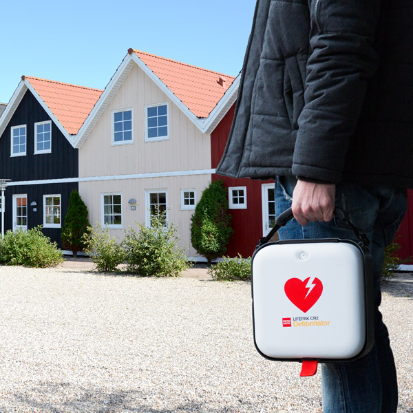 Privatperson håller i en hjärtstartare i ett bostadsområde.