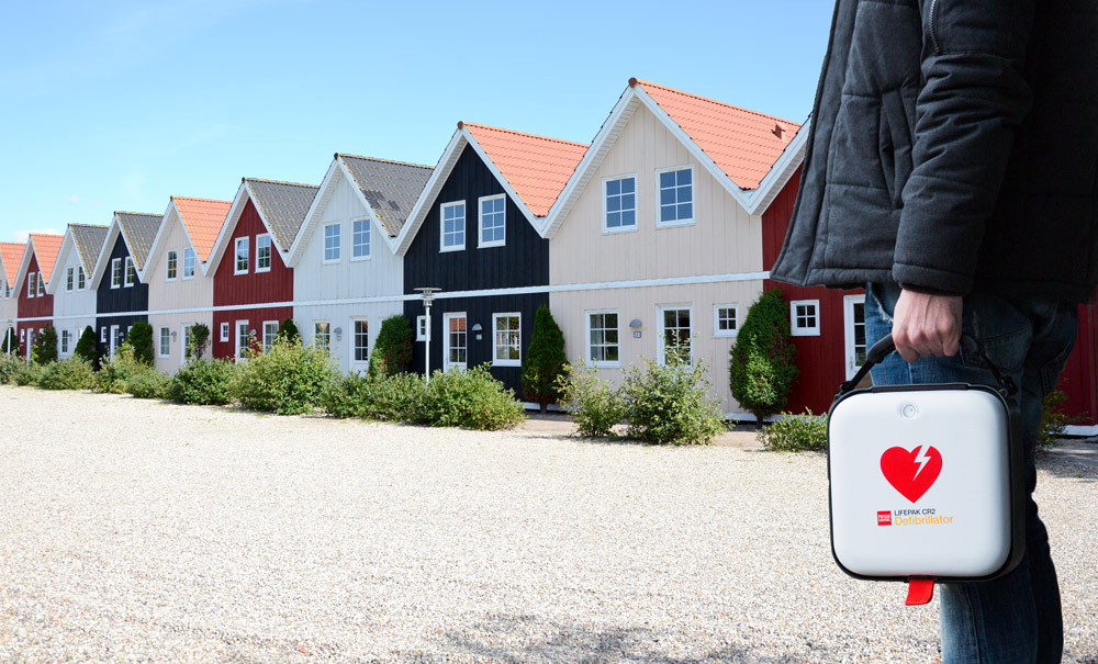 Privatperson håller i en hjärtstartare i ett bostadsområde.