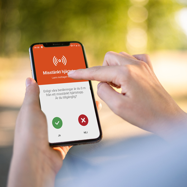 En mobil där skärmen visar ett inkommande larm om hjärtstopp i appen SMS-livräddare. 