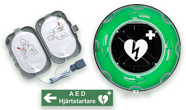 Tillbehör till hjärtstartare en grön plastlåda med ett vitt hjärta, en grön skylt med ordet hjärtstartare på och vita elektroder i grå box. 
