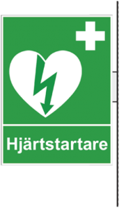 En grön skylt som visar symbolen för hjärtstartare samt har texten "hjärtstartare". 